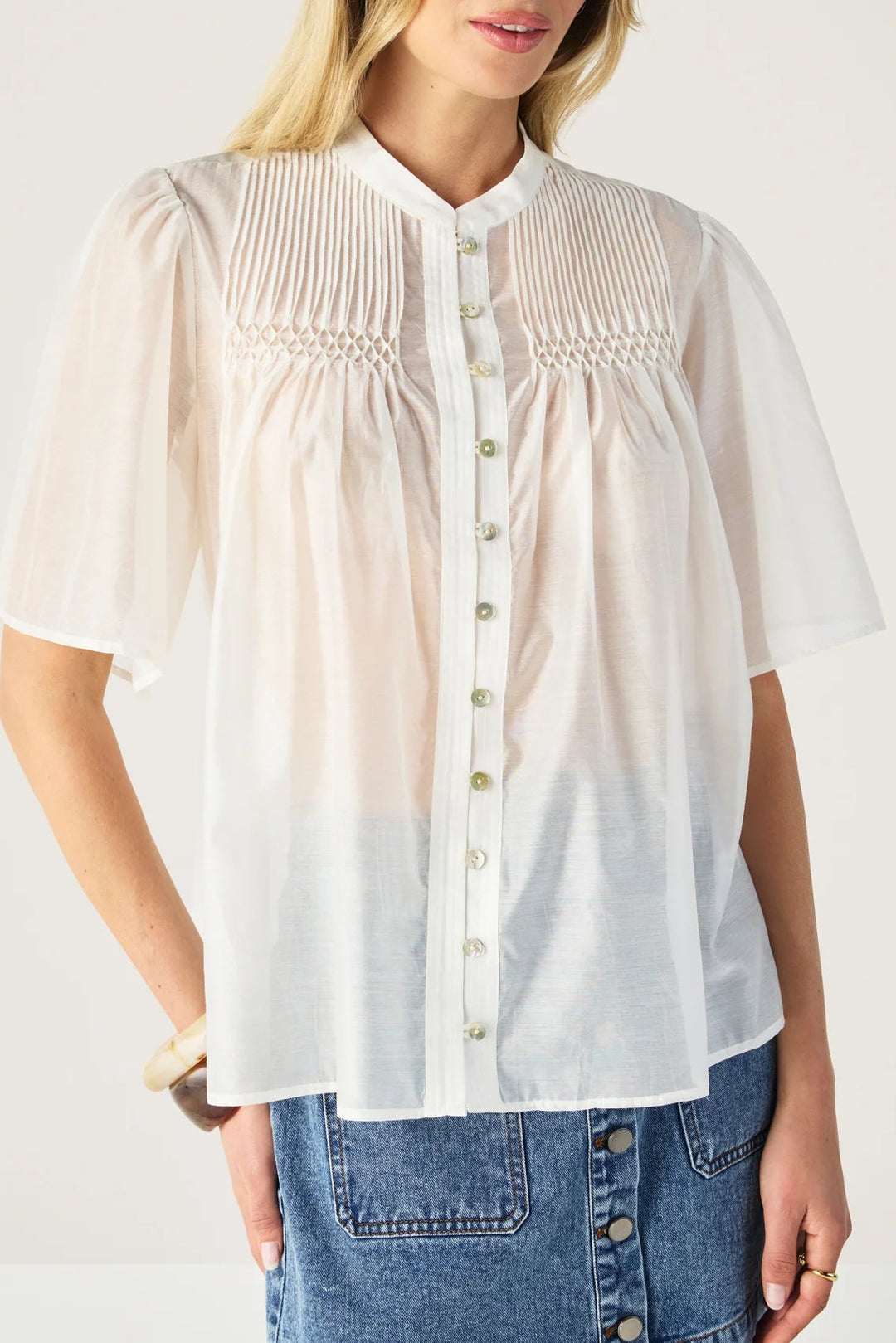 Woman wearing a sheer white blouse with a plain background