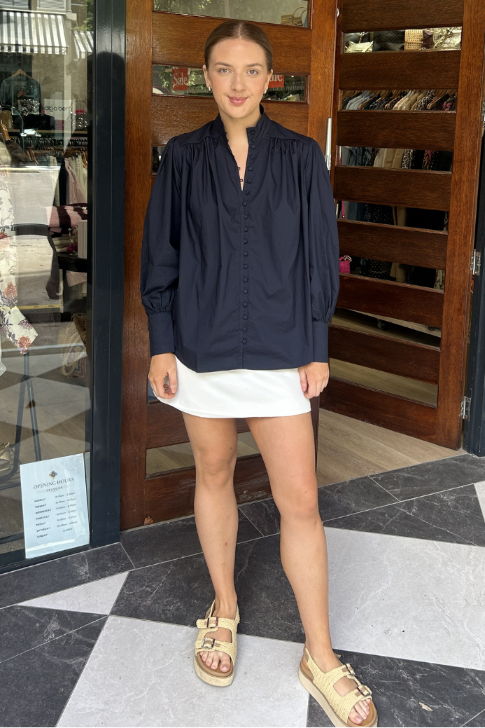 Woman standing in front of a store entrance with mannequins and clothing displayed.