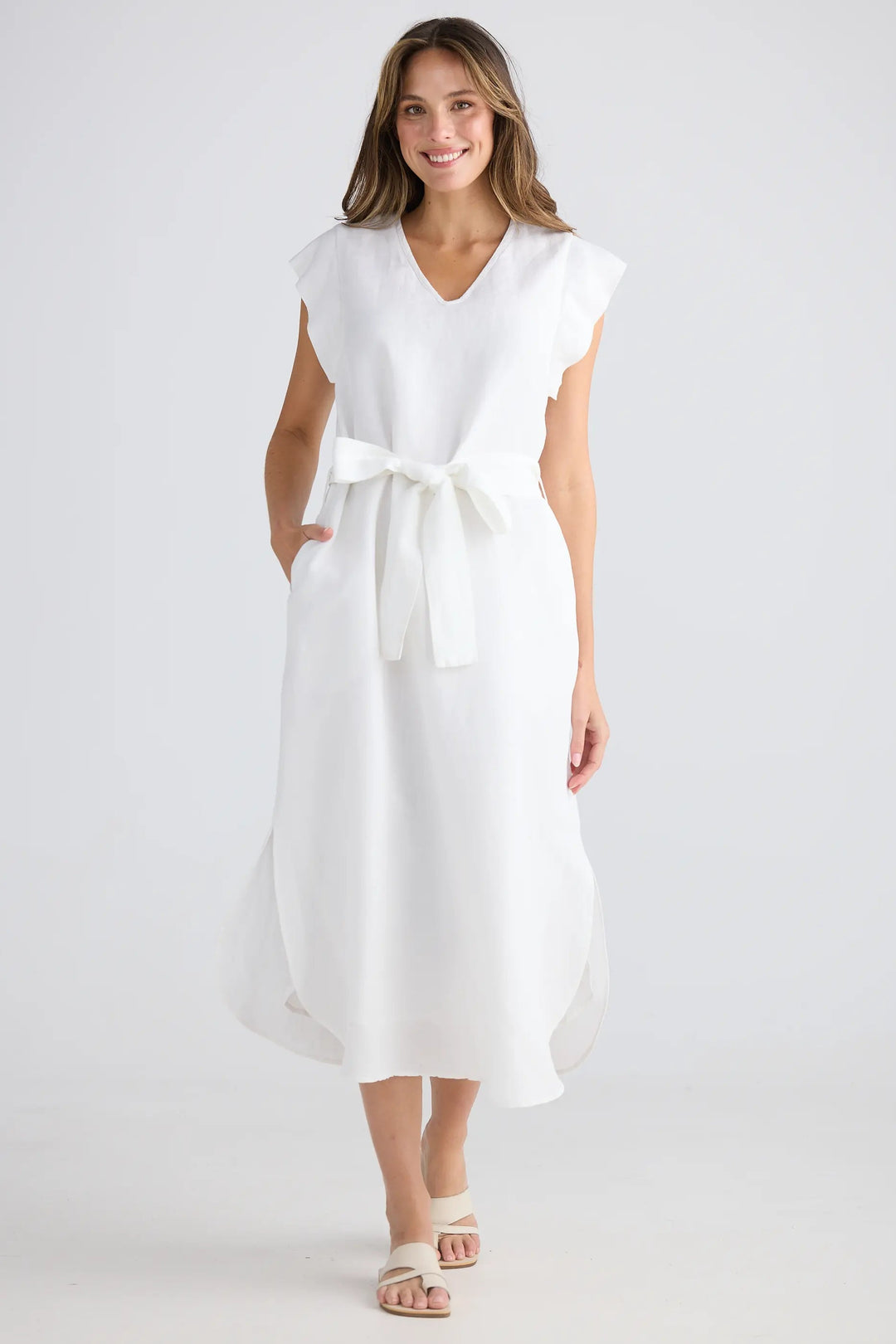 Woman wearing a white dress with a belt on a plain background