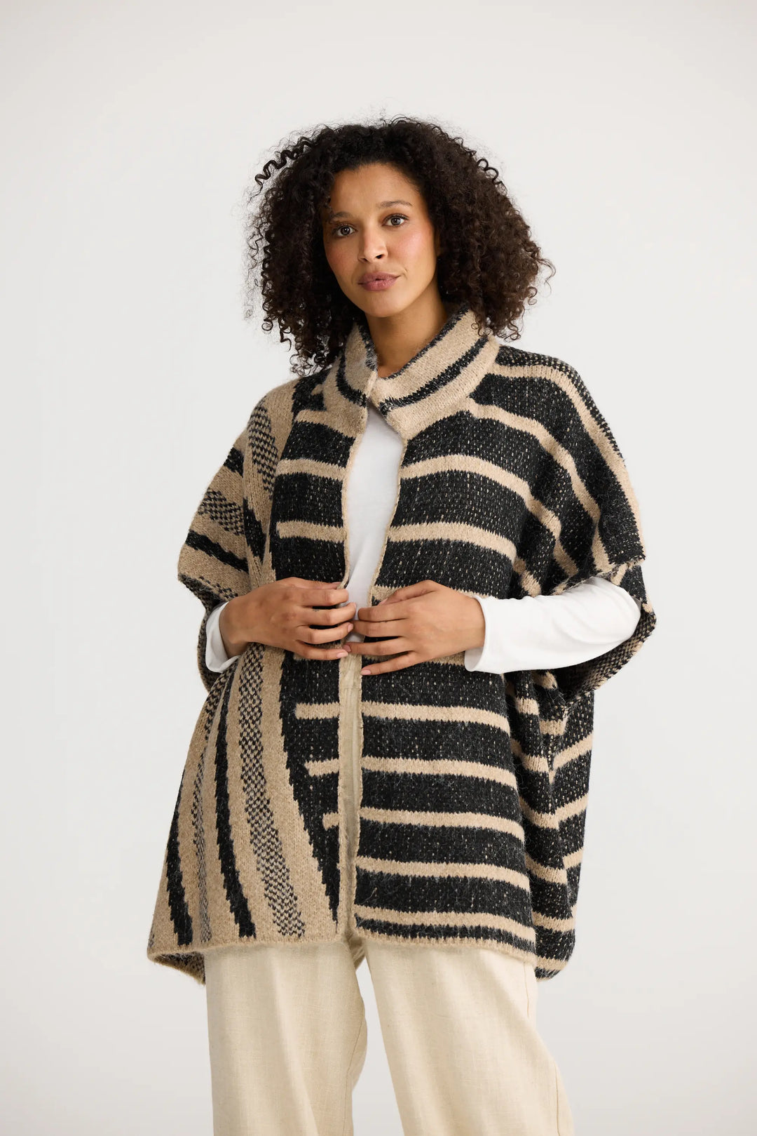 Woman wearing a striped poncho against a white background
