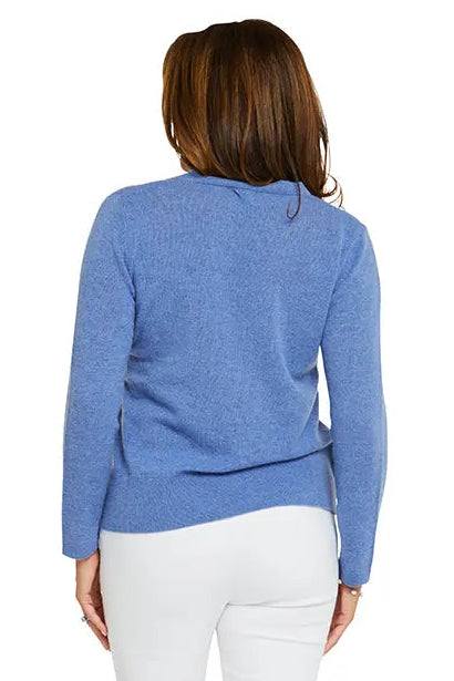 Woman wearing a blue sweater and white pants on a white background