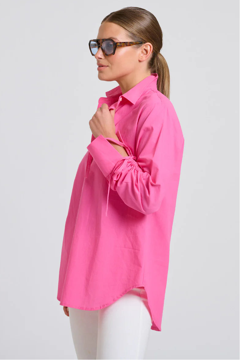 Woman wearing a bright pink shirt on a light gray background
