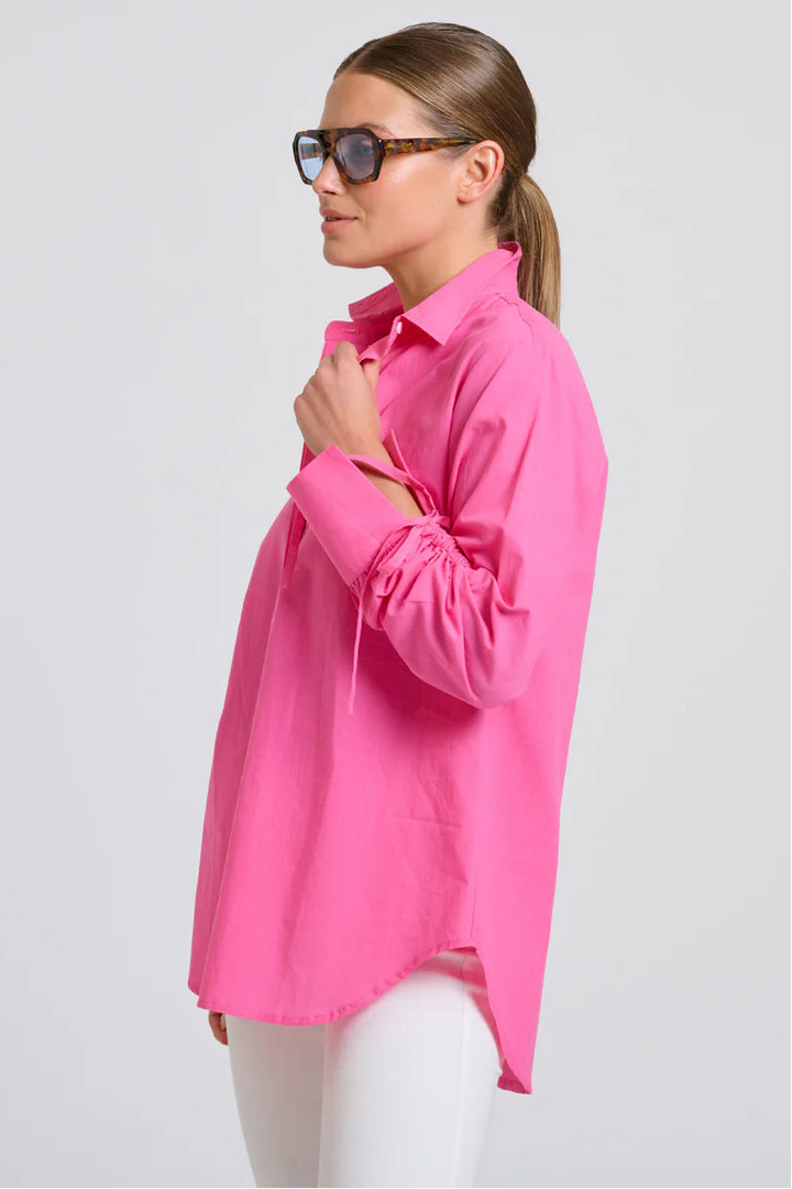Woman wearing a bright pink shirt on a light gray background