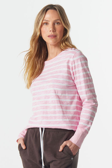 Woman wearing a pink striped sweater and brown pants on a white background