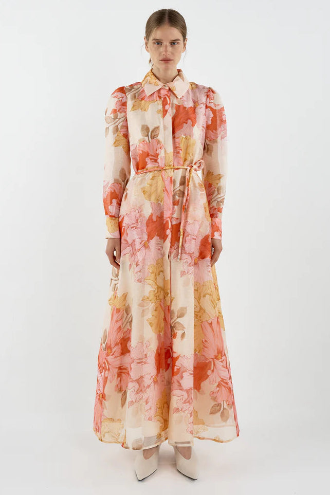 Woman wearing a floral dress with orange and yellow patterns on a white background