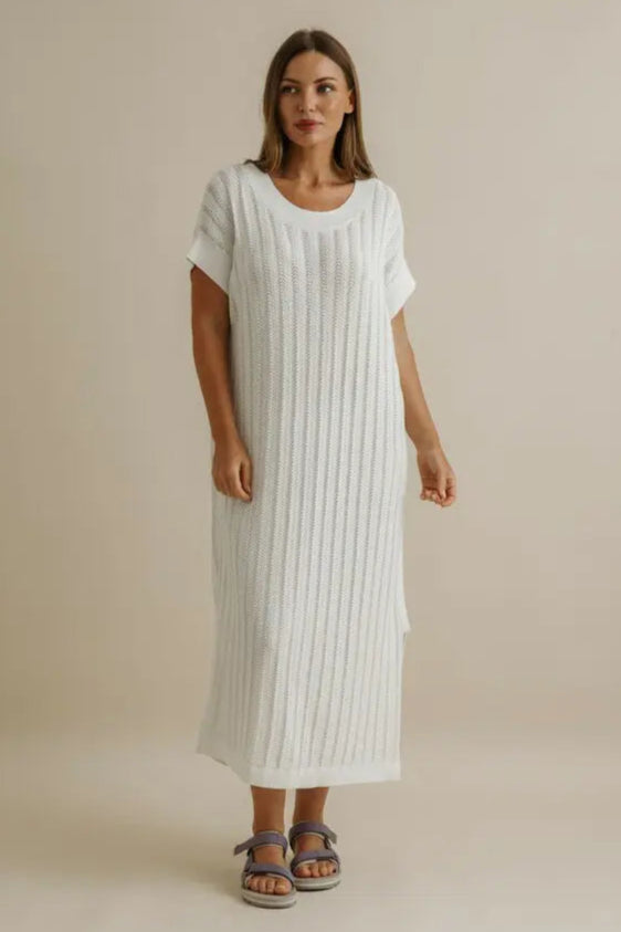 Woman wearing a white dress against a beige background