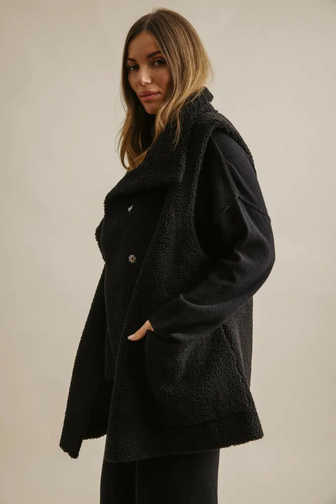 Woman wearing a black coat against a plain background