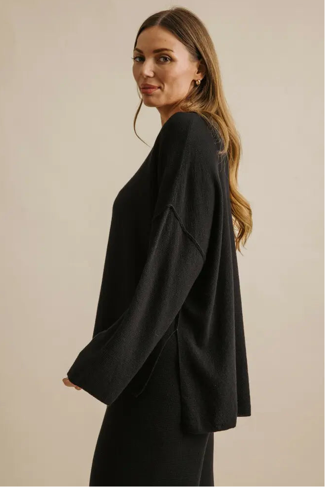 Woman wearing a black outfit against a beige background