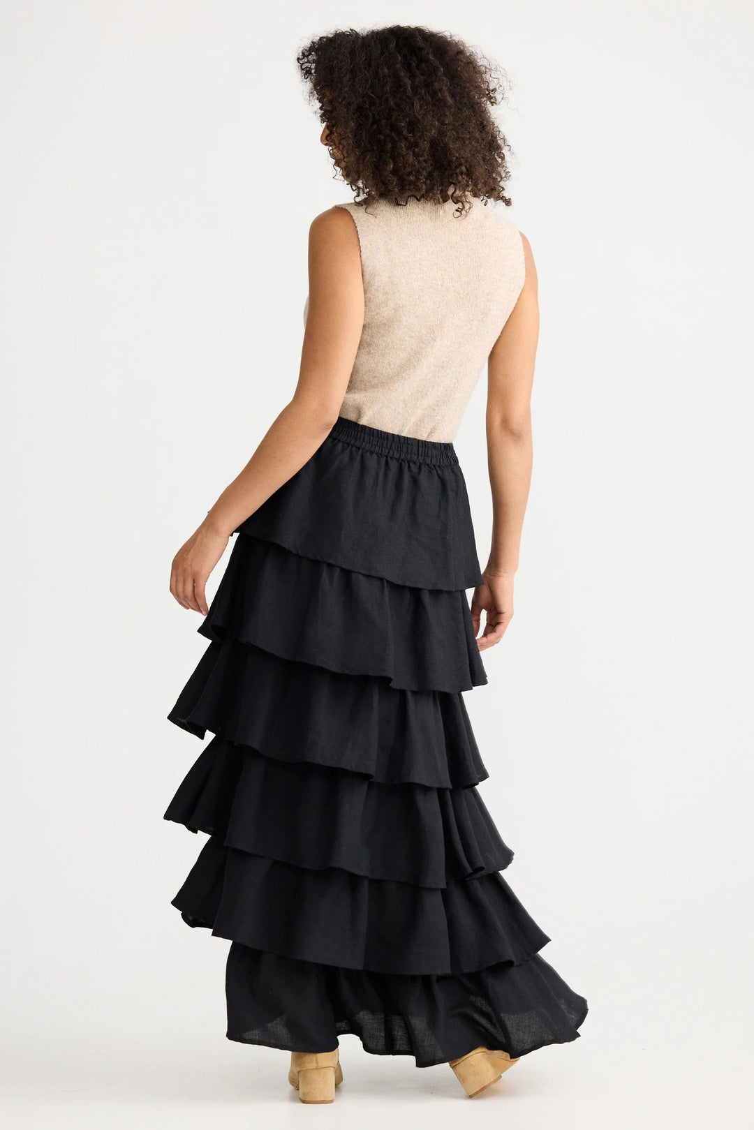 Woman wearing a black tiered skirt with a beige top on a white background