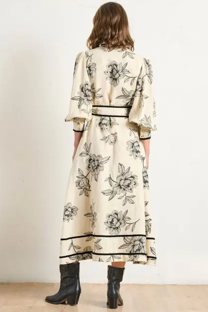 Woman wearing a floral dress with black accents on a plain background