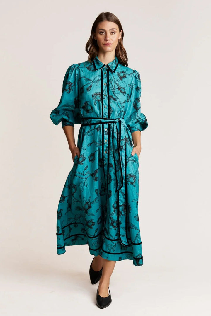 Woman wearing a teal dress with black patterns on a white background