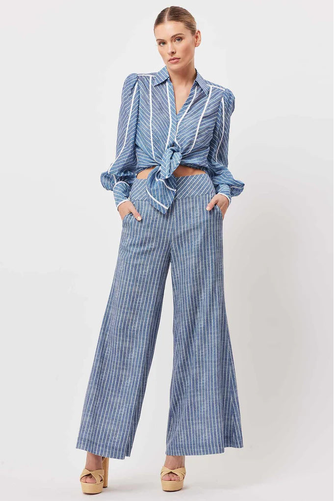 A model wearing blue wide-leg pants with a pinstripe pattern. The pants have a high waist and wide legs, suitable for both formal and casual occasions.