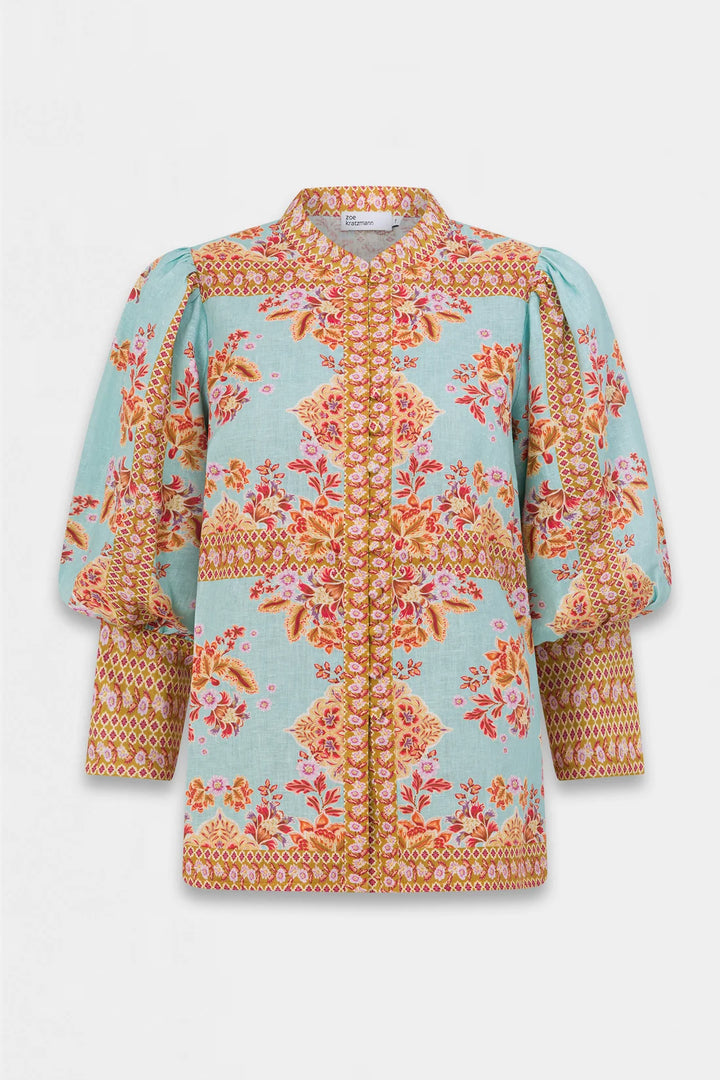 A light blue cropped jacket featuring a vibrant orange, pink, and yellow floral and geometric pattern, with puffed balloon sleeves and a stand collar, shown against a light gray background.