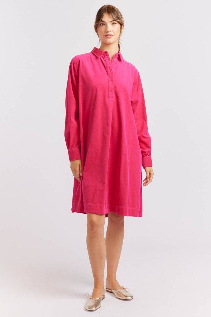 A person wearing a magenta pink knee-length cord dress with a half placket button down front.