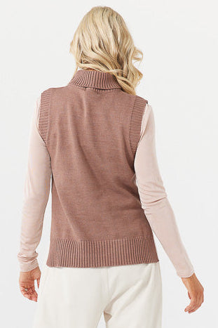 Person wearing a brown knitted vest over a light pink long-sleeve shirt on a white background