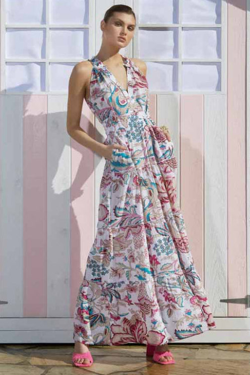 A woman standing in front of a striped structure wearing a floral maxi dress with a v-neckline.